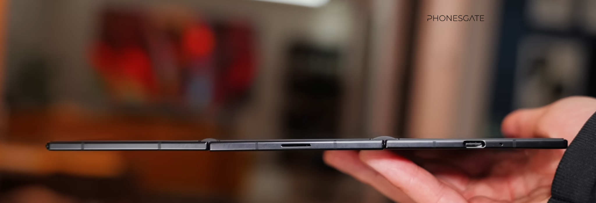 Thin side profile of a Samsung foldable shown opened in a hand