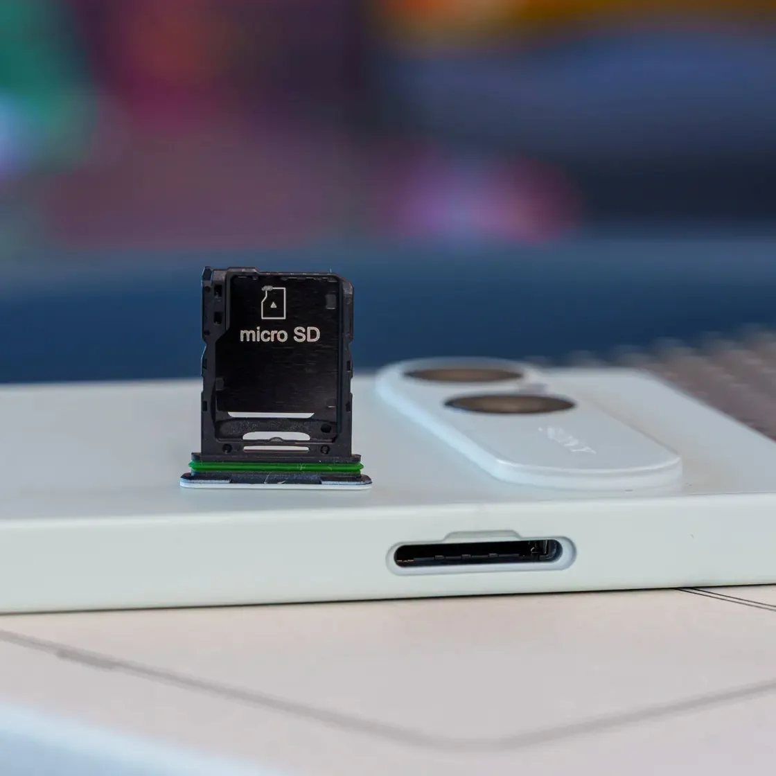 Close-up of Xperia 10 VIII microSD tray beside the white phone